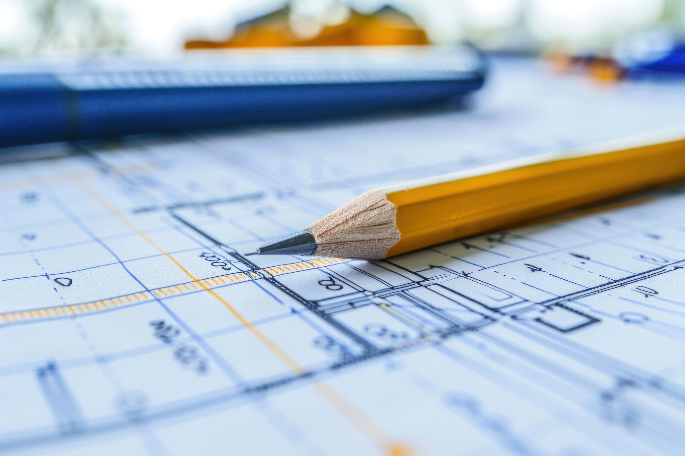 Close-up of a pencil resting on a blue architectural drawing